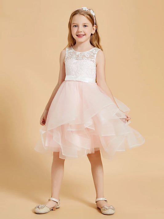 Heowos blush pink flower girl dress with an ivory lace illusion bodice, small satin waist bow and knee-length cascading tulle ruffles.