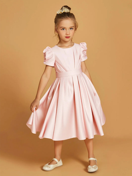 Heowos blush pink satin flower girl dress with a round neckline, short puff sleeves, folded bodice, wide waistband and full knee-length skirt.
