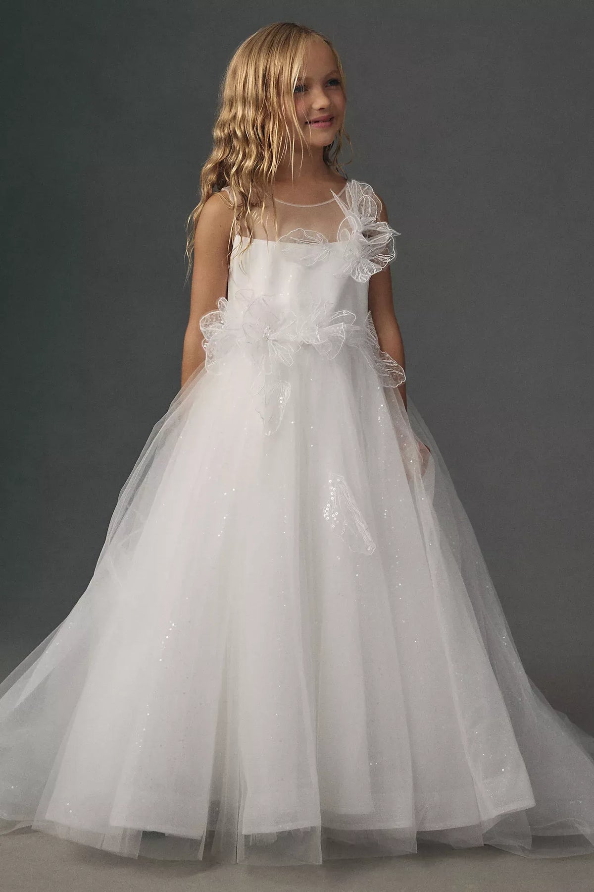 Heowos white flower girl ballgown with an illusion neckline, sleeveless bodice, 3D shoulder and waist flowers, and glitter tulle skirt.
