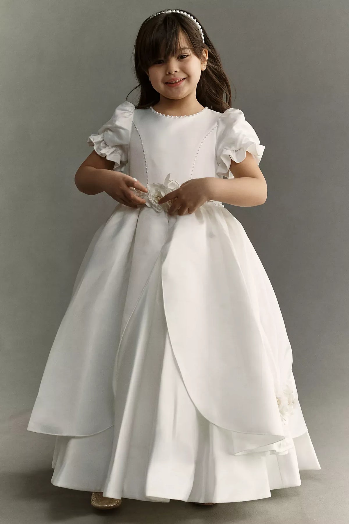 Heowos white first communion ballgown with ruffled puff sleeves, beaded bodice trim, floral waist accents and a split-front overskirt.